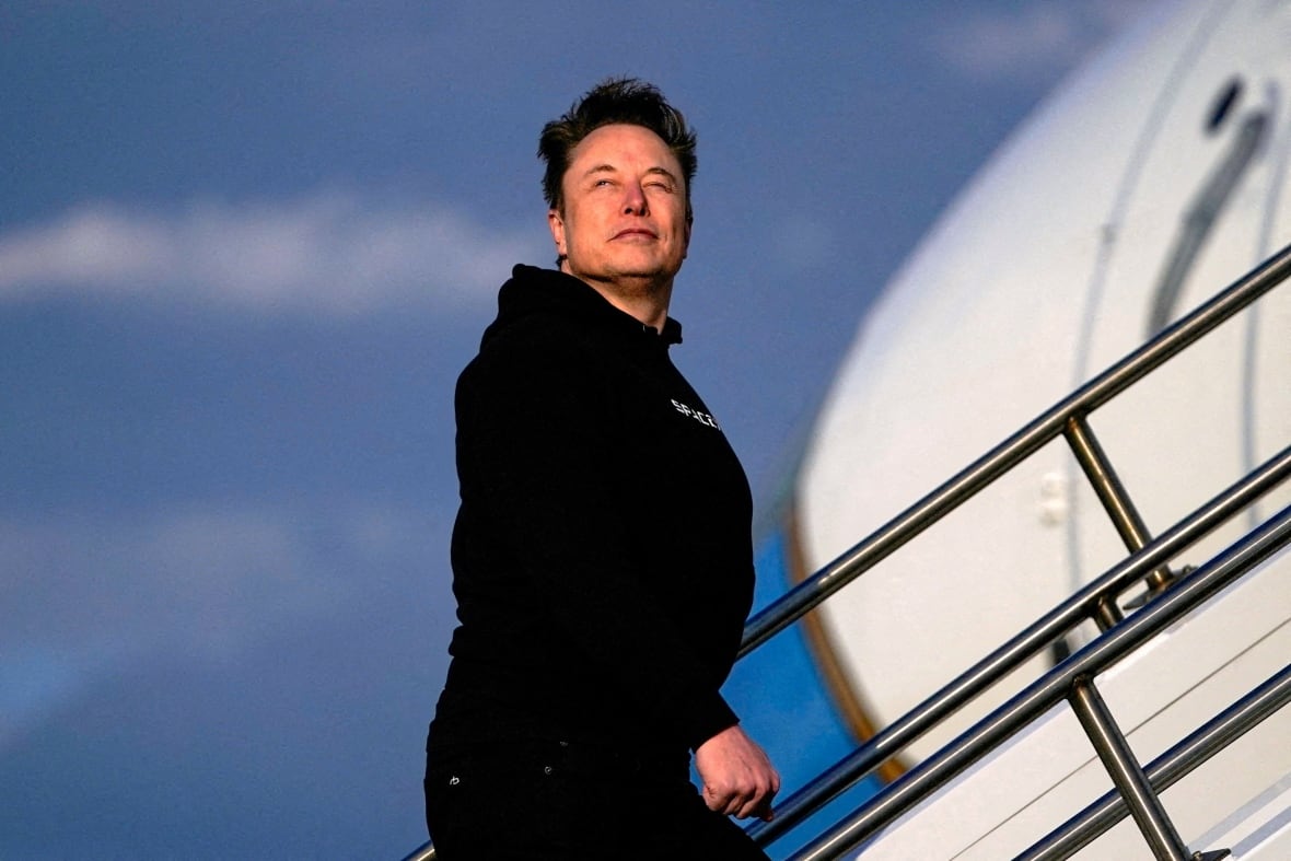 A man in dark clothing is shown ascending stairs leading to an airplane.