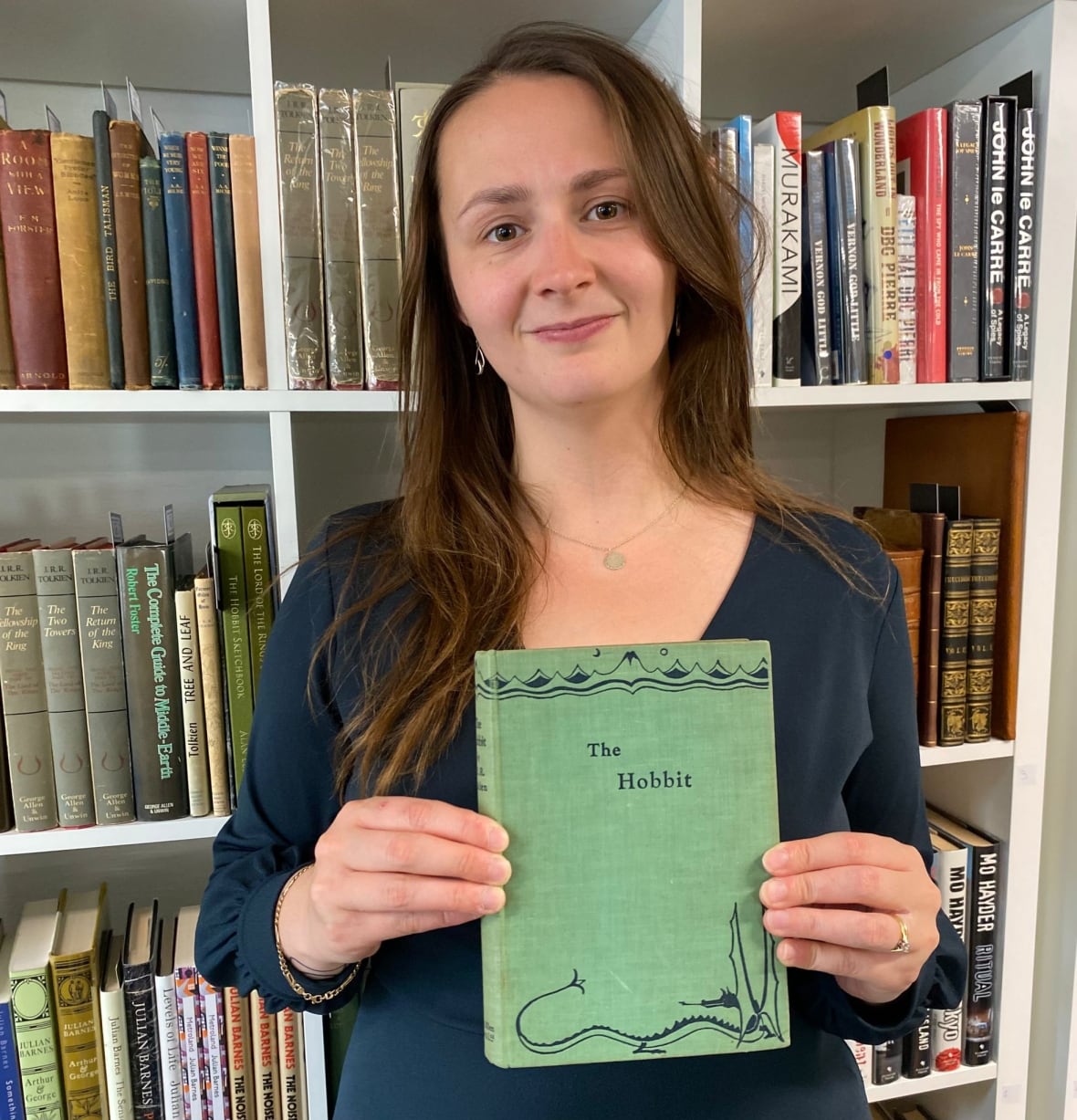 A woman holds a book with a green cover. 