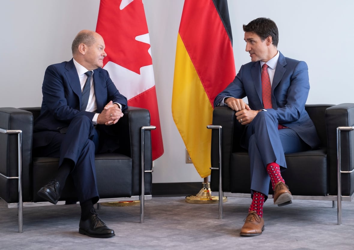 Two men in front of flags. 
