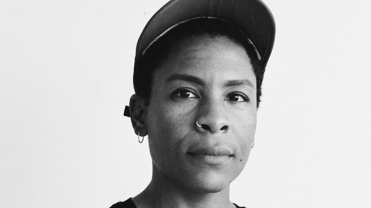 A black and white photo of a Valérie Bah wearing a black t-shirt and baseball cap. 