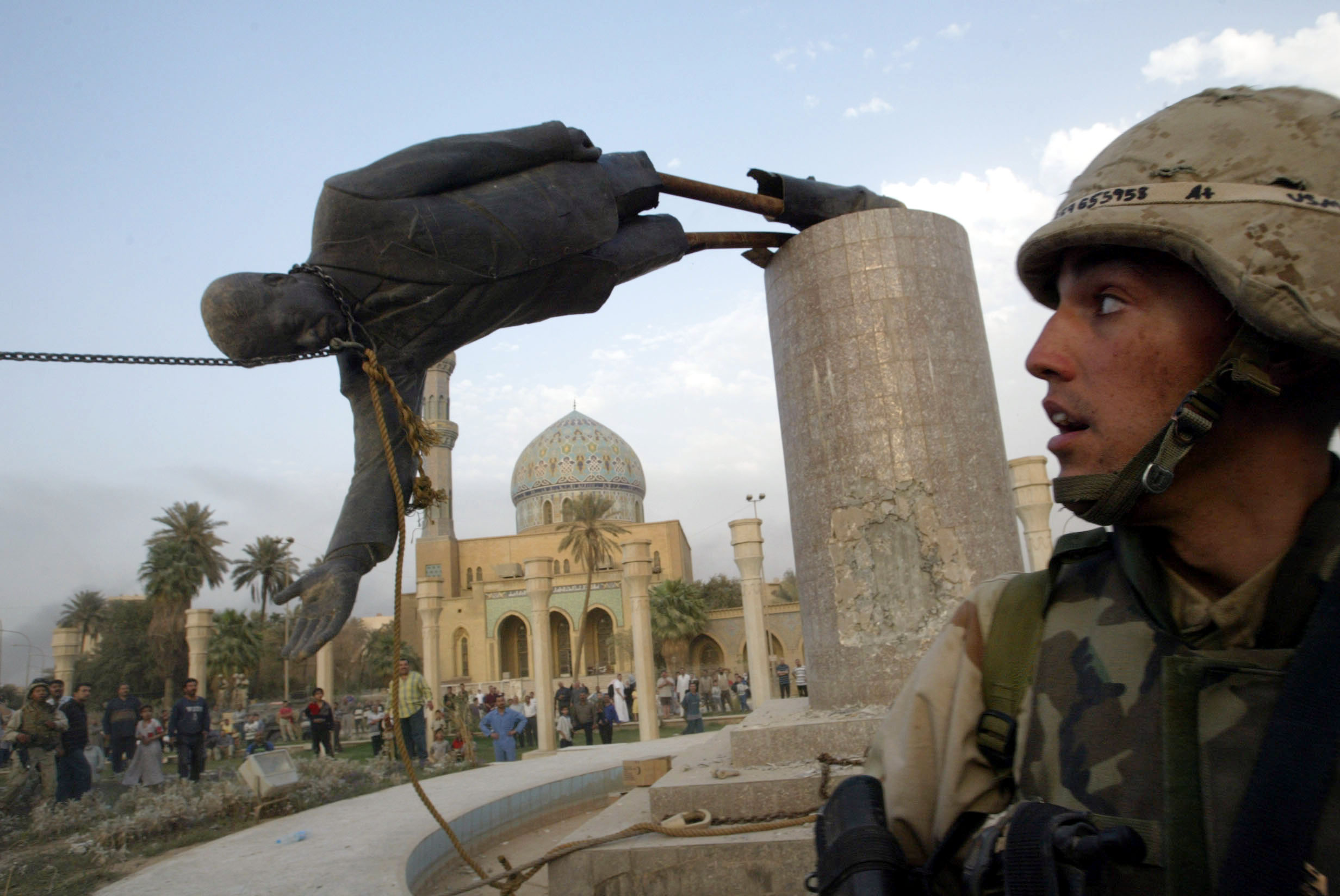 A U.S. SOLDIER WATCHES A STATUE OF PRESIDENT SADDAM HUSSEIN FALL IN.CENTRAL BAGHDAD.