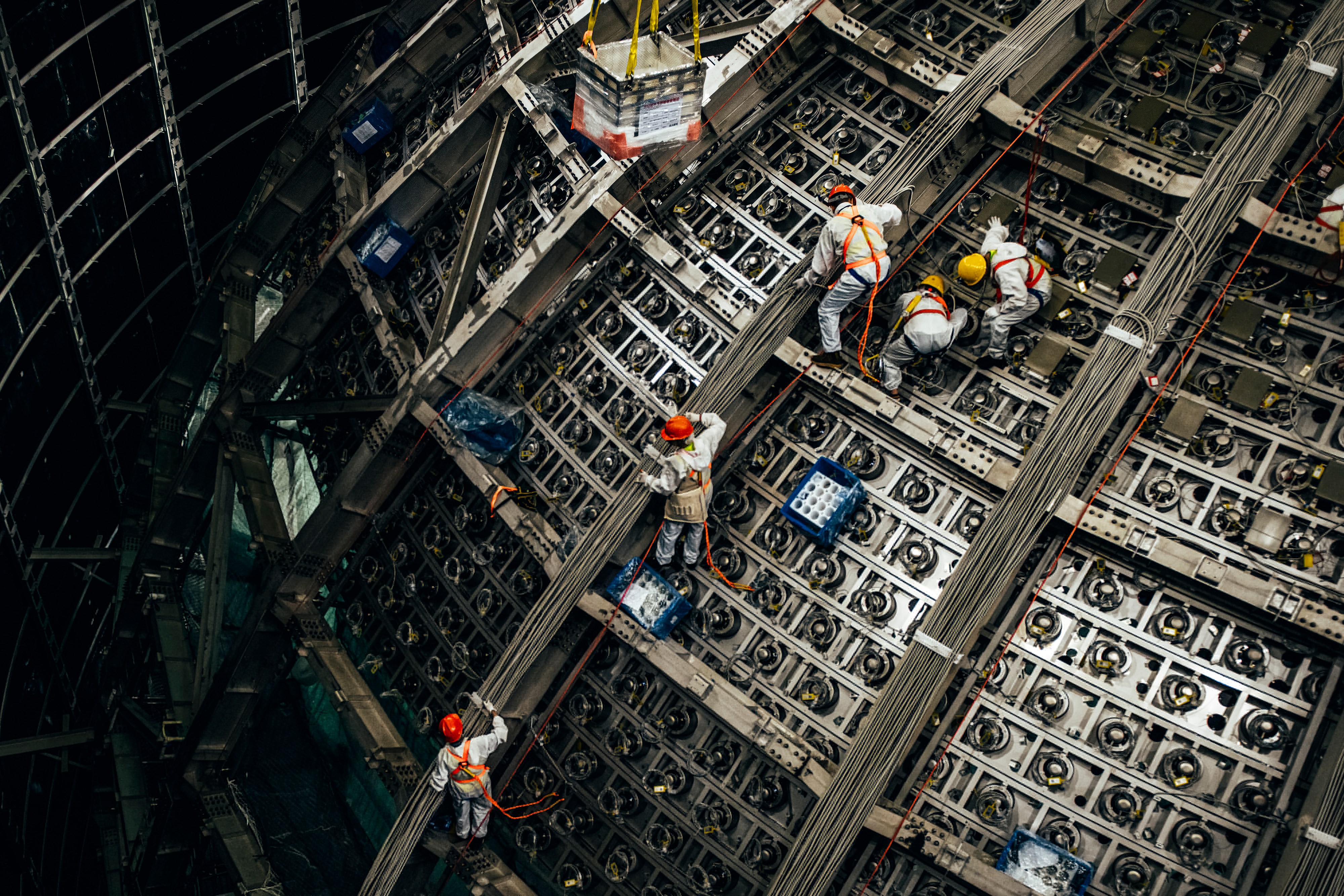 Workers installing components at the JUNO neutrino observatory construction site.