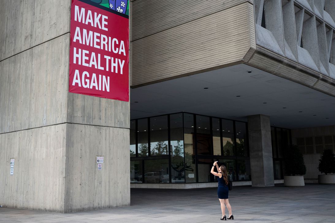 A woman takes a photo of the Make America Healthy Again sign hanging outside the Department of Health and Human Services building in Washington, DC, on September 15.
