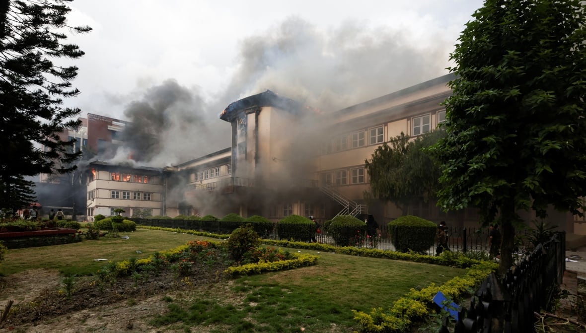 A large, three-storey building is engulfed in smoke and flames. 