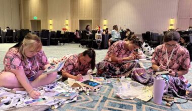 A group of friends bejewel the covers of their favorite romance novels while clad in book-themed pajamas during the Romantically Yours Convention’s pajama party event. (Hafsa Quraishi/Here & Now)