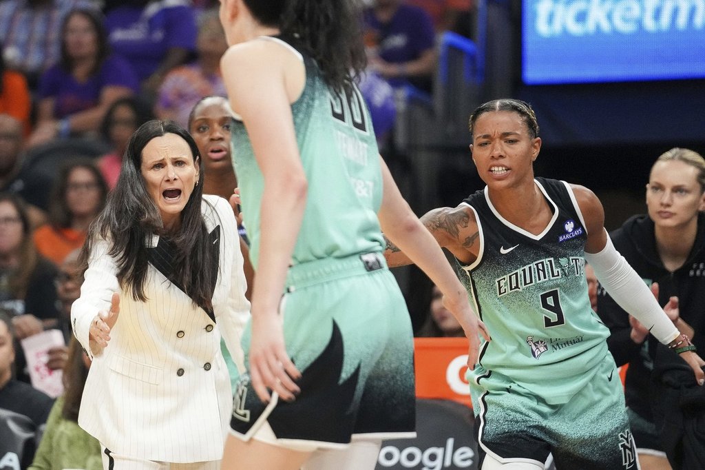New York Liberty head coach Sandy Brondello, left, and Natasha Cloud (9) cheer on Breanna Stewart, center, during the first half of Game 1 against the Phoenix Mercury in the first round of the WNBA basketball playoffs Sunday, Sept. 14, 2025, in Phoenix. (AP Photo/Darryl Webb)