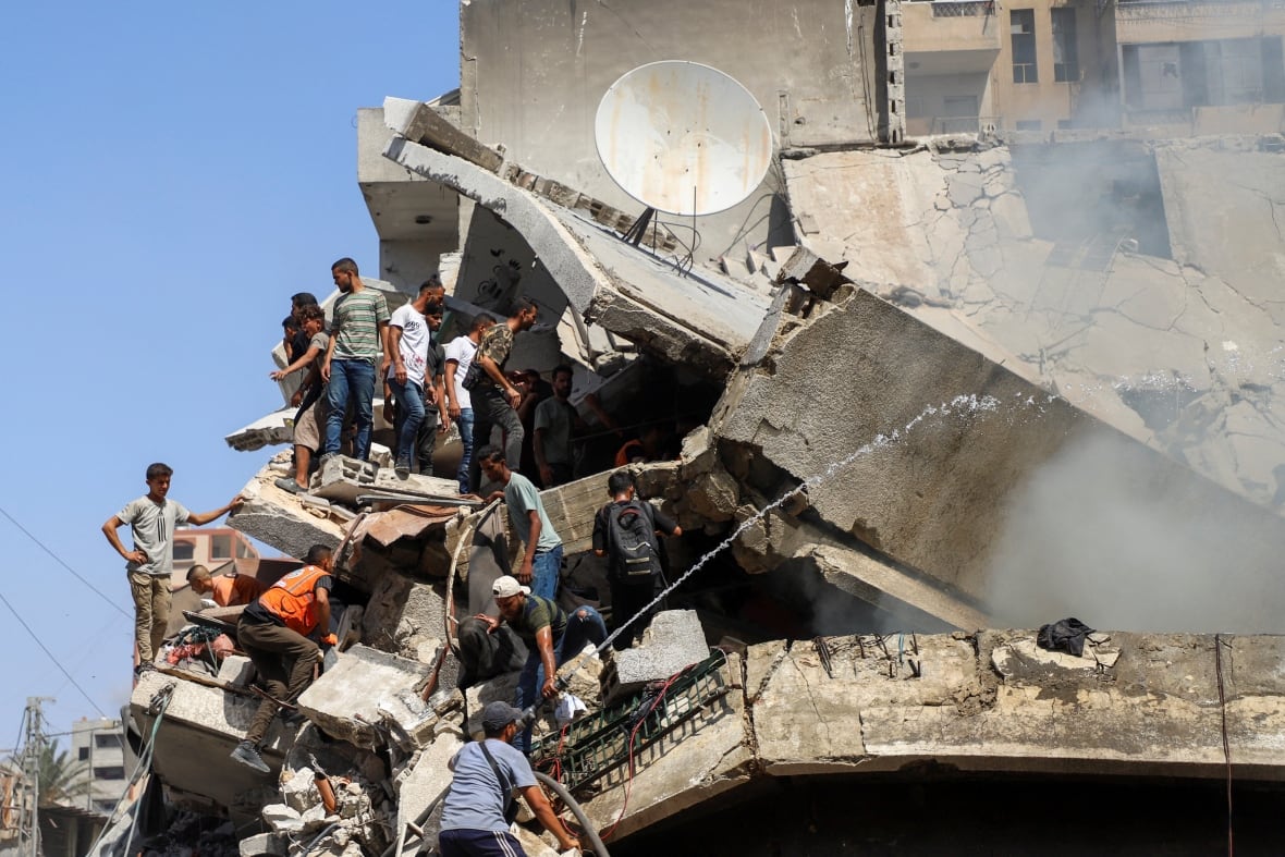 People search for victims in a destroyed building.