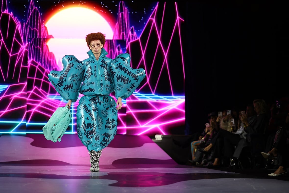 A model walks the runway, where a turquoise outfit that looks made with inflatable balloon for sleeves.  