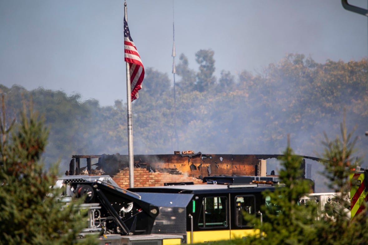 Emergency service vehicles surround a destroyed building. 