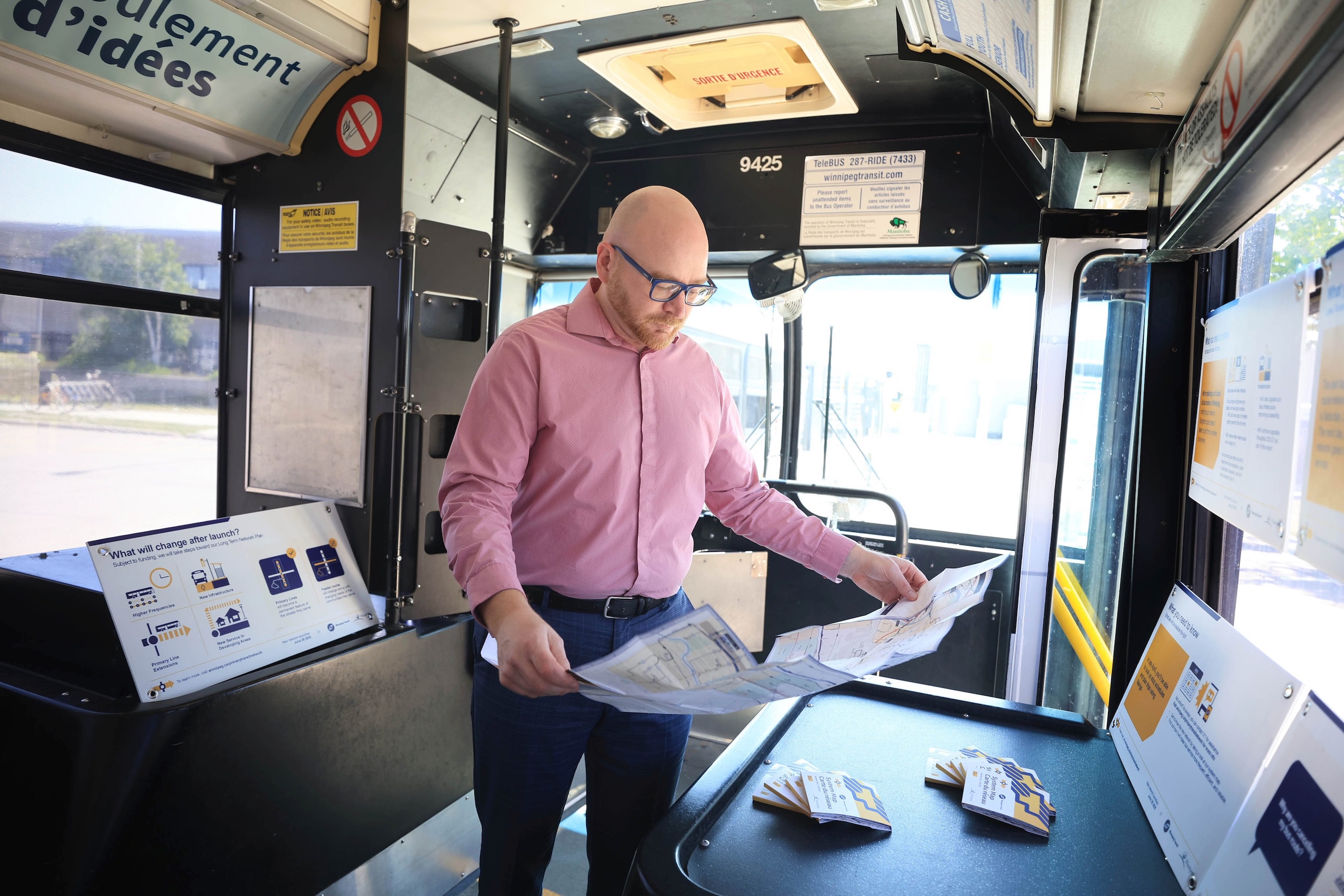 Bjorn Radstrom, who designed the new Winnipeg Transit network, holds a paper map of bus routes while standing in a Winnipeg bus