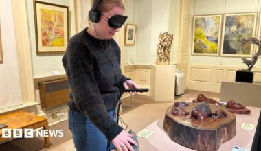 A close up of the arms of a woman flicking through a box of colourful record albums in a record shop