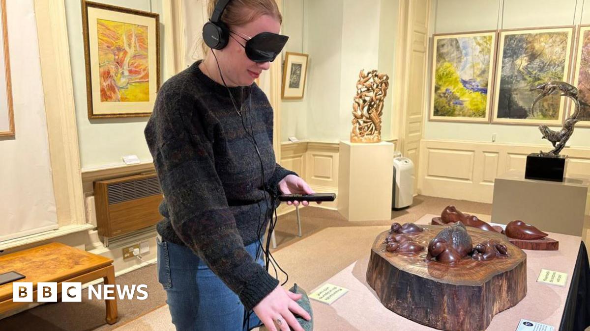 A close up of the arms of a woman flicking through a box of colourful record albums in a record shop