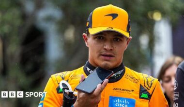 Lando Norris walking in his McLaren suit after qualifying in Baku and talking into a mobile phone