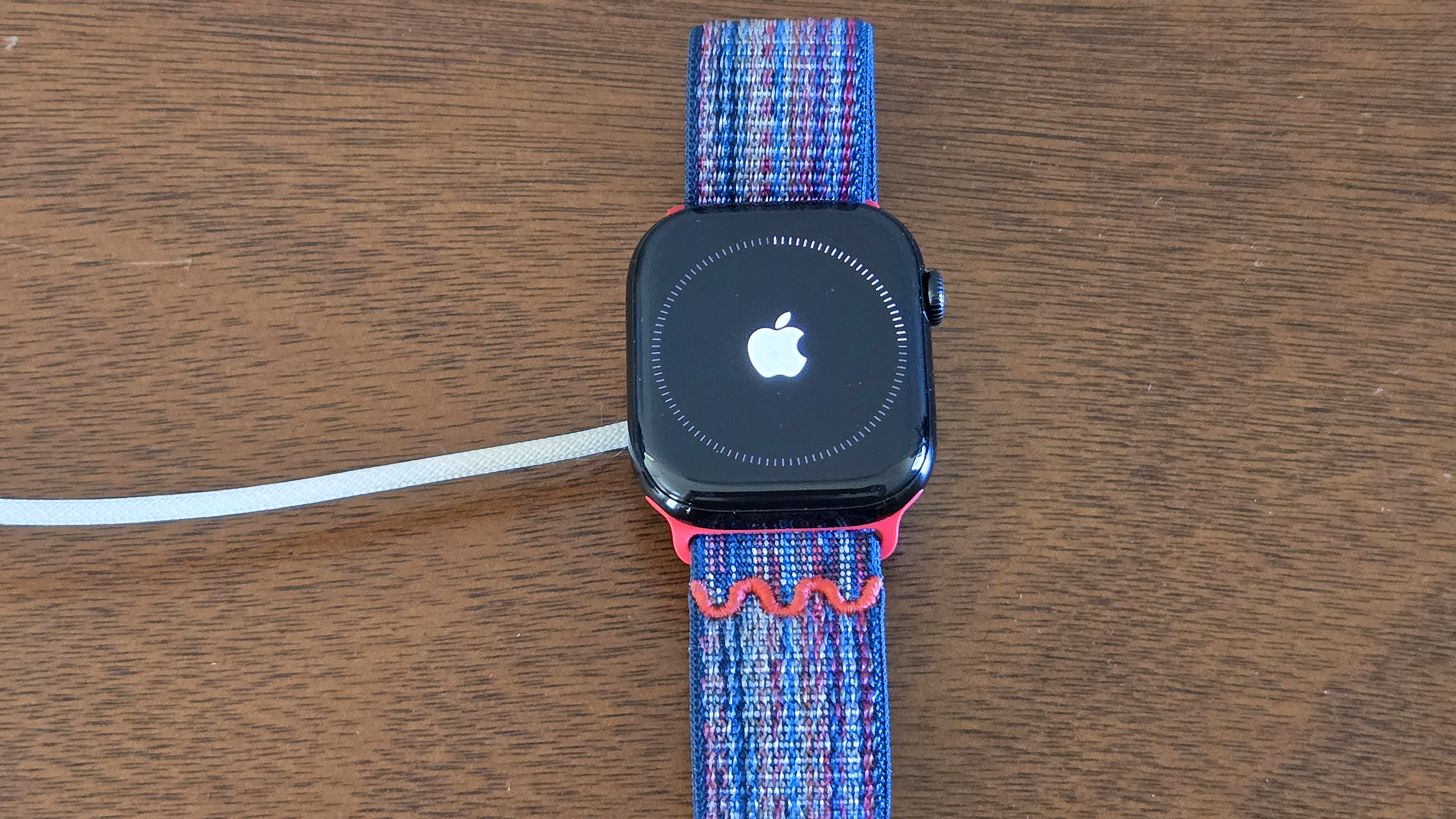 Close-up of the installation process for watchOS 26 showing an Apple Watch Series 10 and iPhone 12 Mini