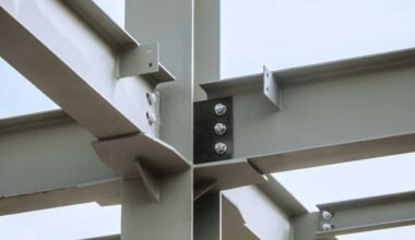 Steel joints. Mounting bolted connection of steel beams before welding. Metal construction covered protective gray primer. Close-up.