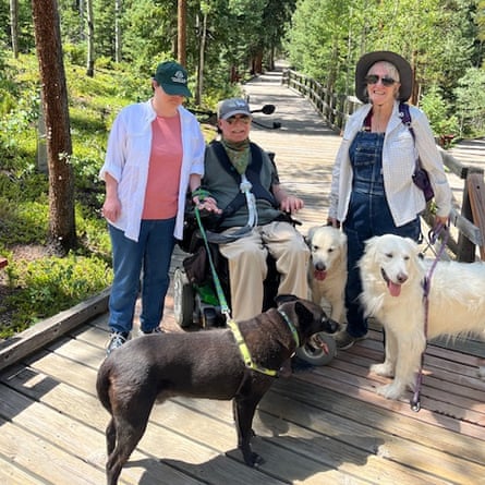 Three people, one in a wheelchair, and three dogs 