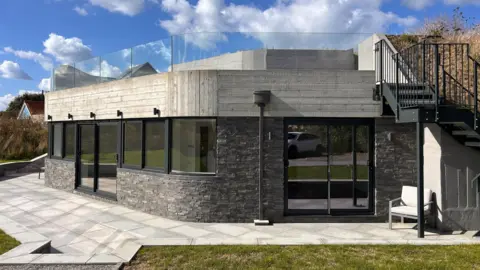 A grey and black house surrounded by white patio 