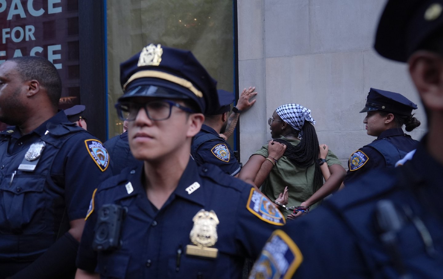 Protester getting arrested and pinned against wall while other police officers turn their back.
