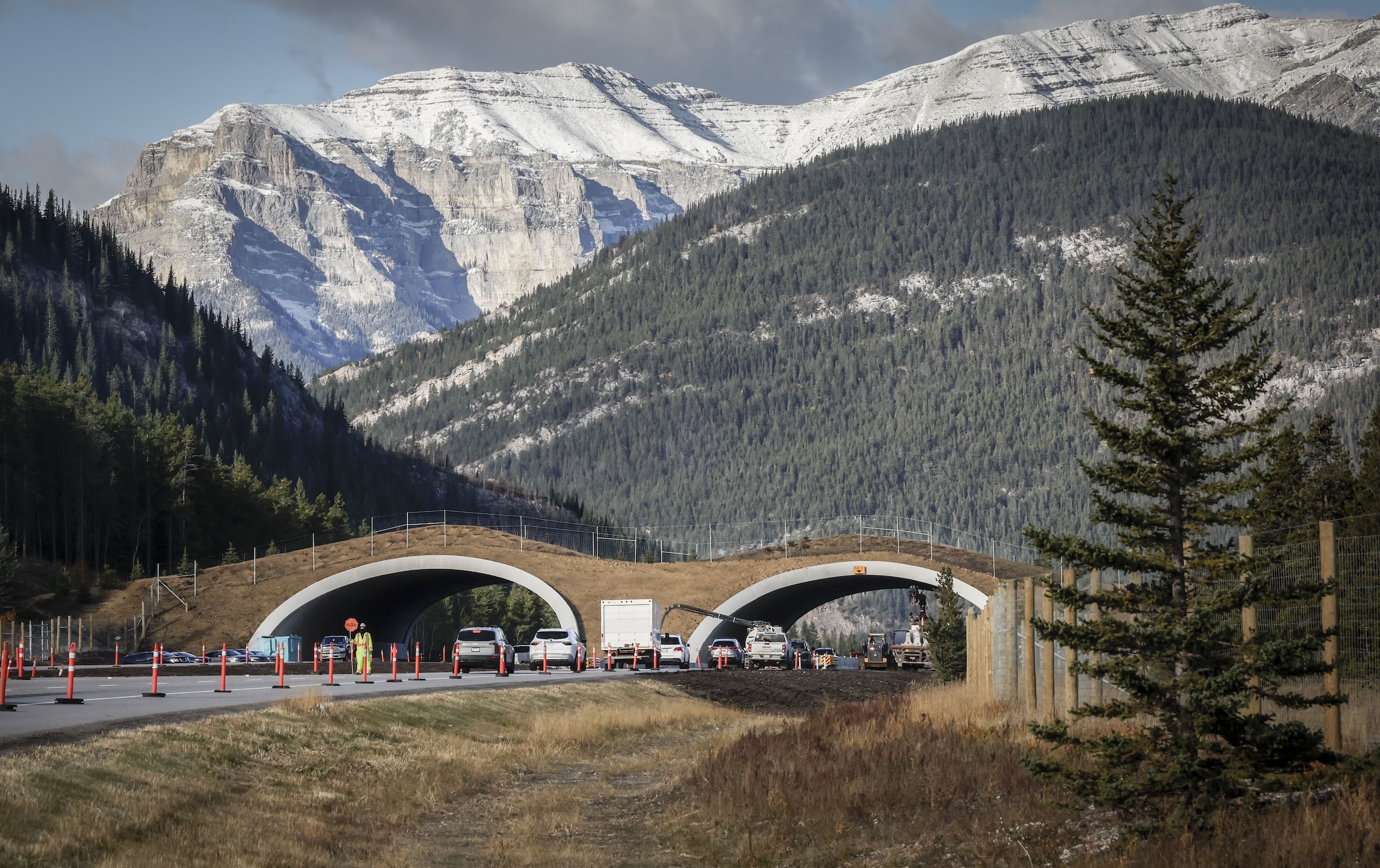 An overpass for wildlife is seen crossing a highway, with the Rocky Mountains rising in the background near Exshaw, Alta.