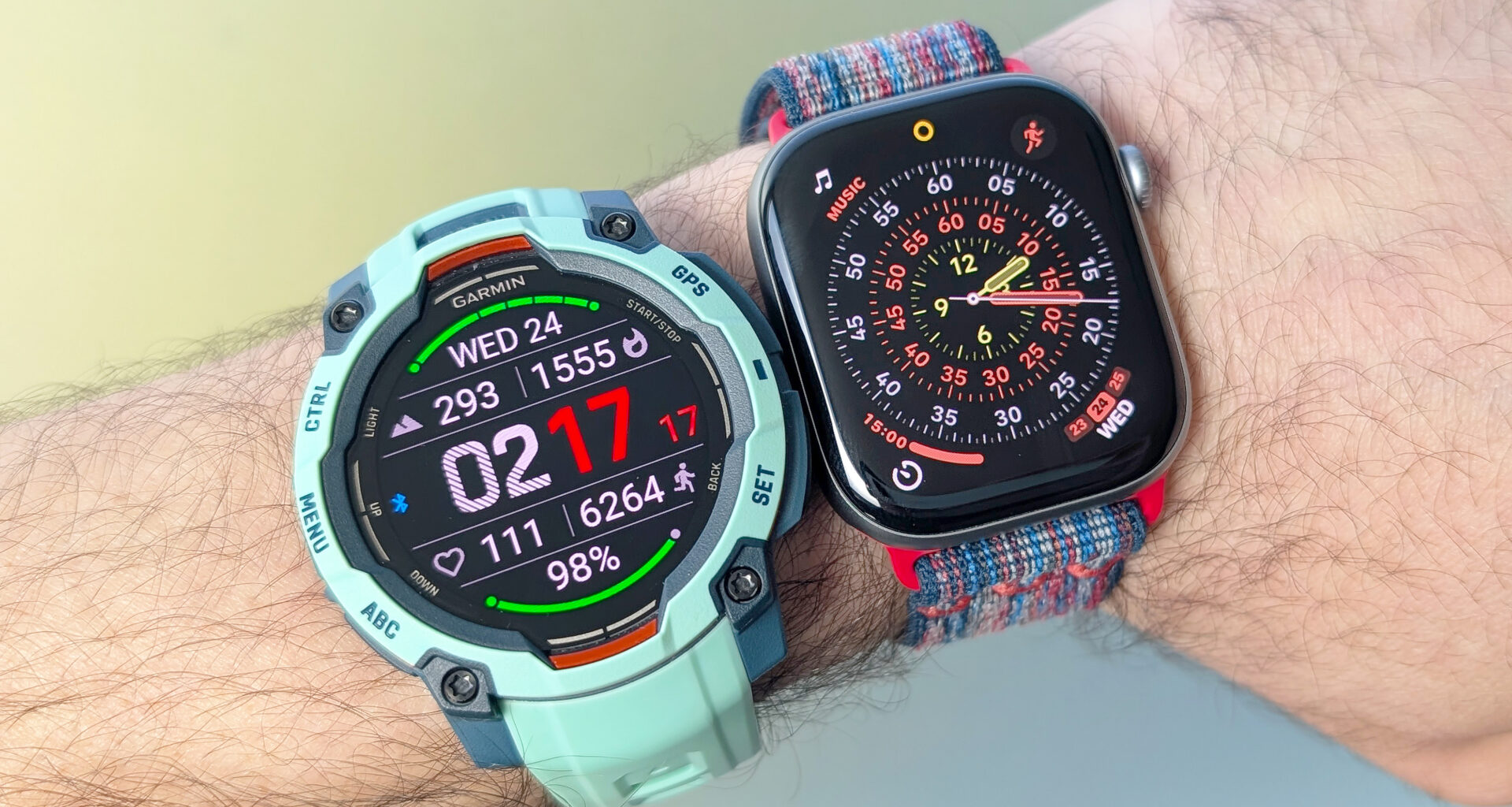 Close-up of the Garmin Instinct 3 next to the Apple Watch Series 11