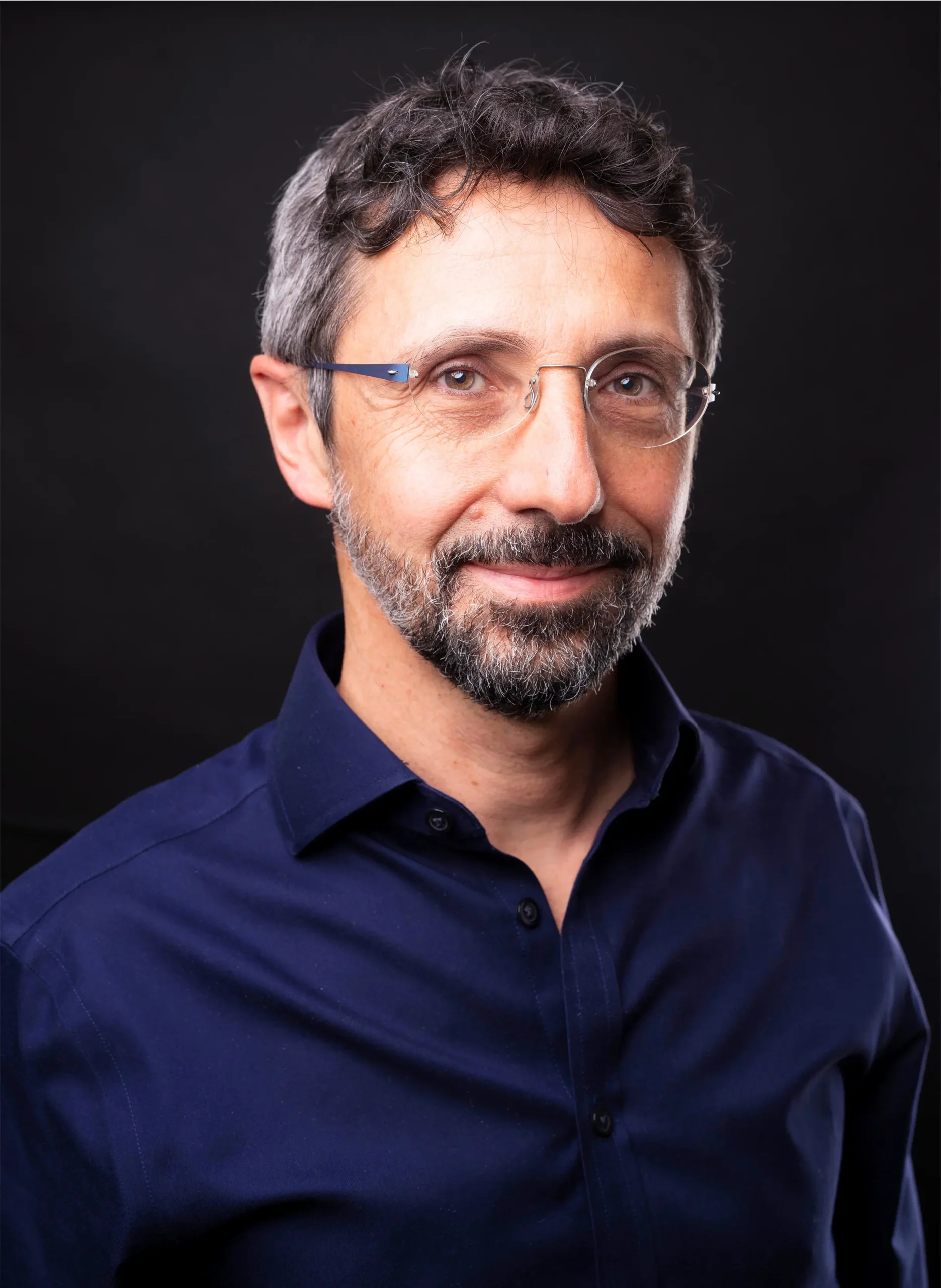 A man with glasses and a beard smiles at the camera.