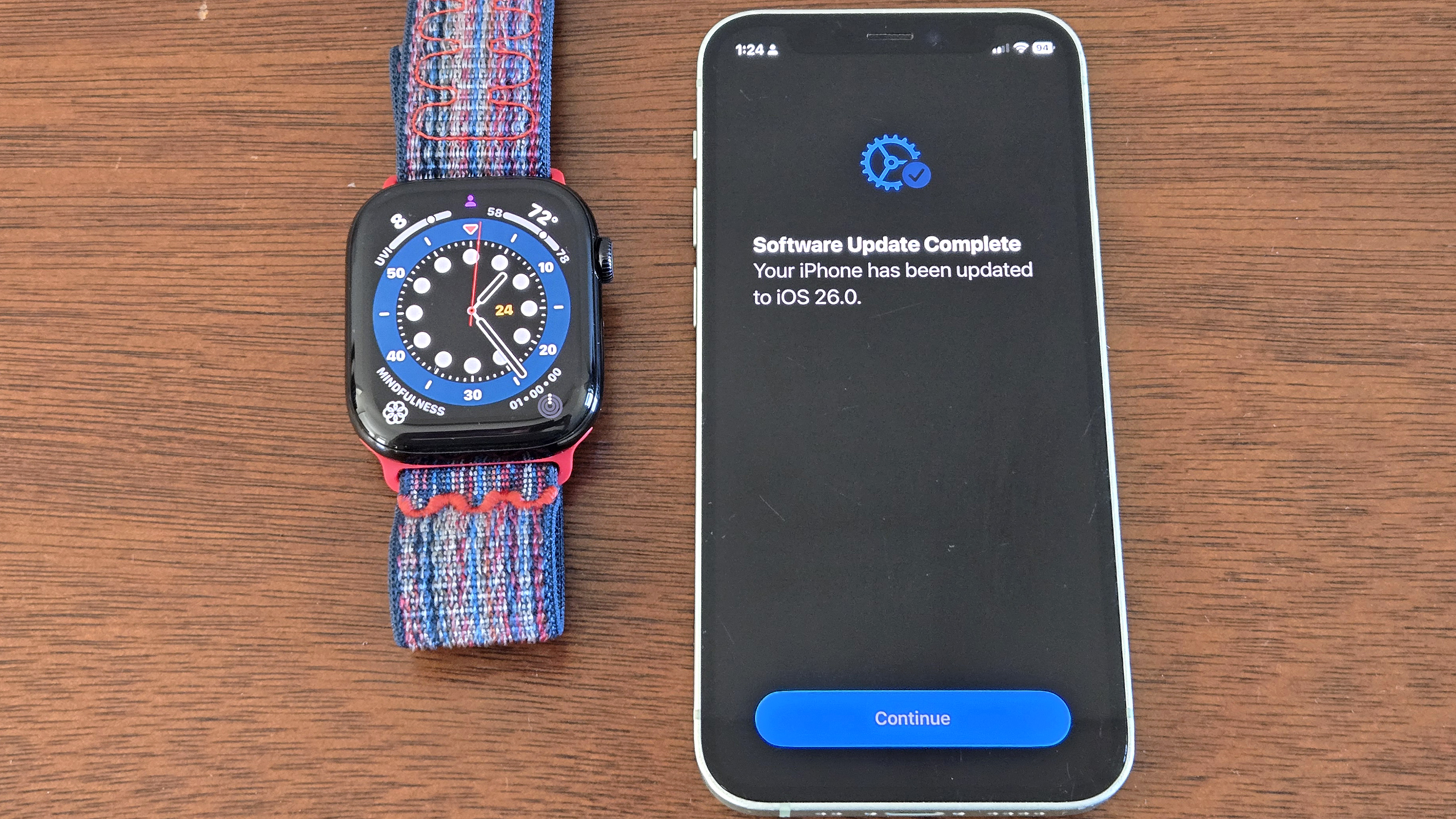 Apple Watch 10 next to an iPhone 12 Mini with a screen informing the user that iOS 26 beta has been successfully installed 