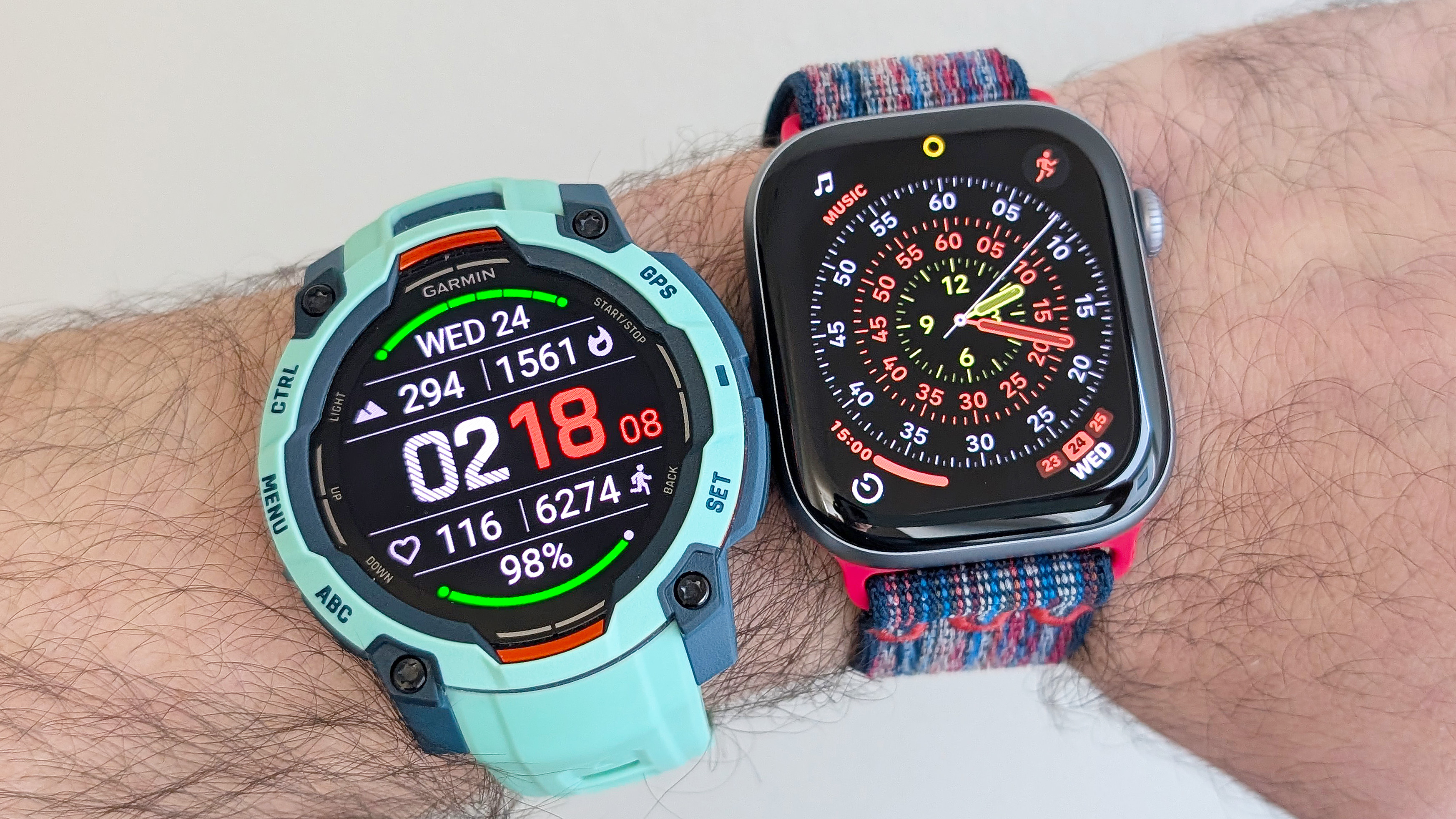 Close-up of the Garmin Instinct 3 next to the Apple Watch Series 11