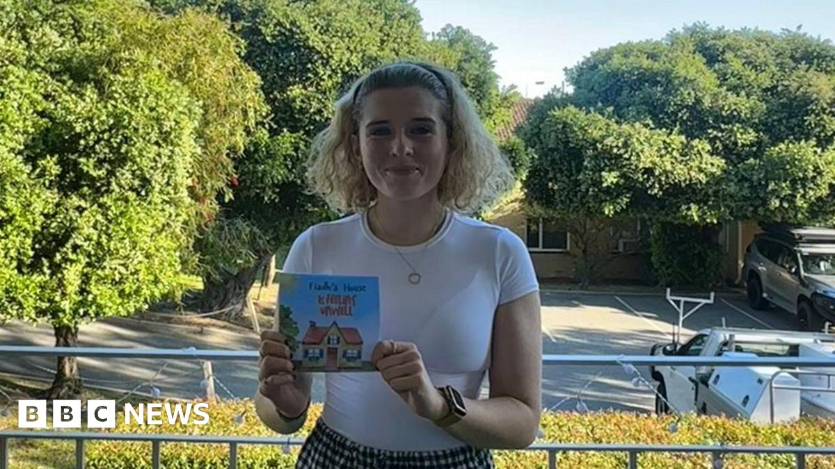 A side profile of a grey house with a number of visible cracks and marks in the wall.
