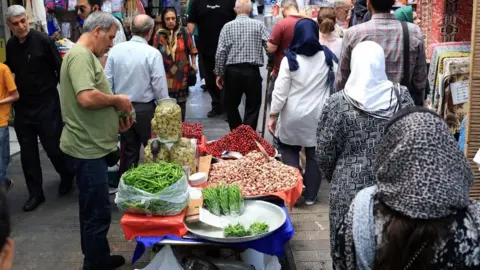 Reuters People walking through a market place in Tehran (file photo)