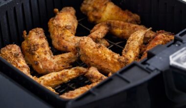 Chicken wings in a black air fryer basket.