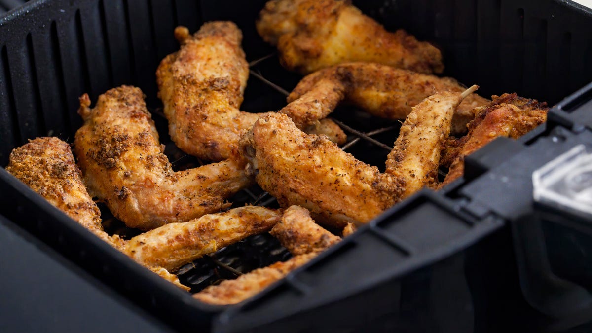 Chicken wings in a black air fryer basket.