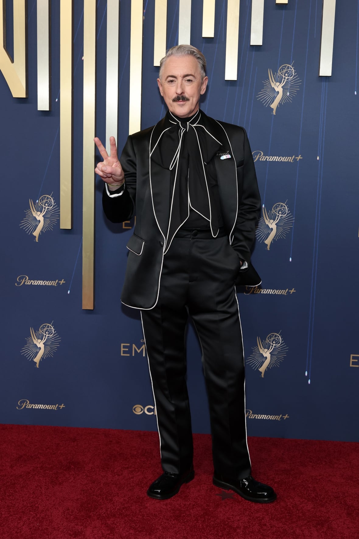 A man in a black suit poses for a photo.