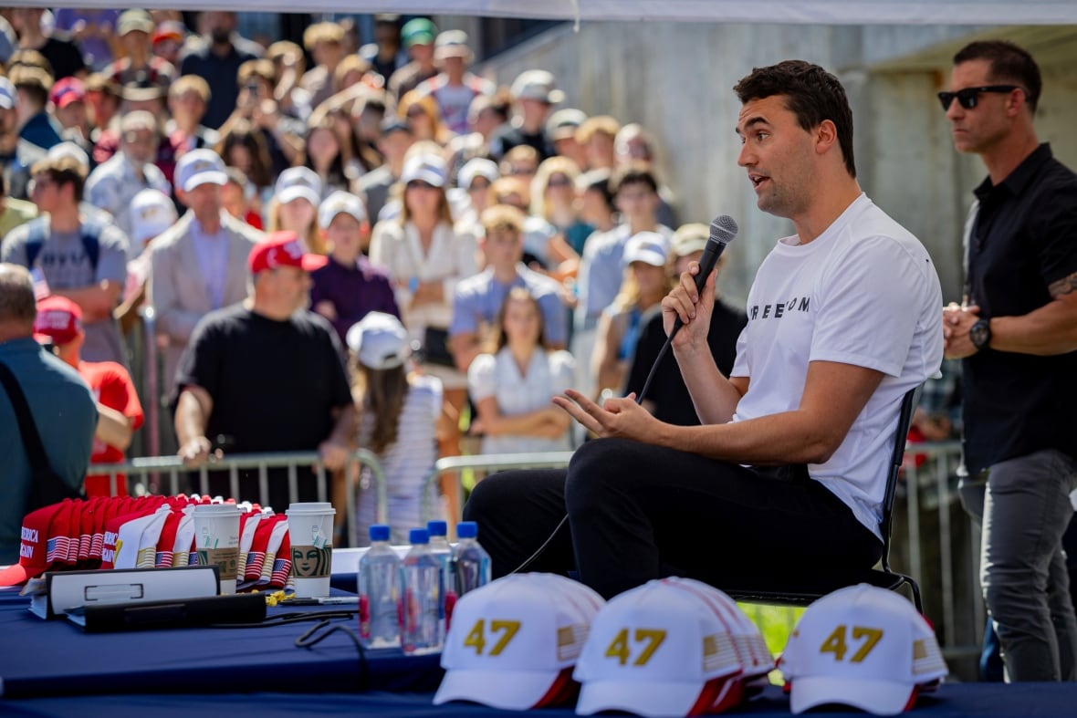 A man speaks in front of a large crowd.