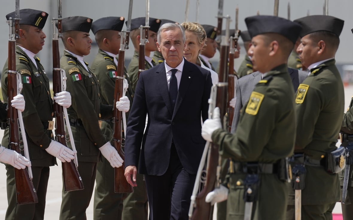 A couple inspects an honour guard each in uniform and wearing white gloves and holding weapons upright.