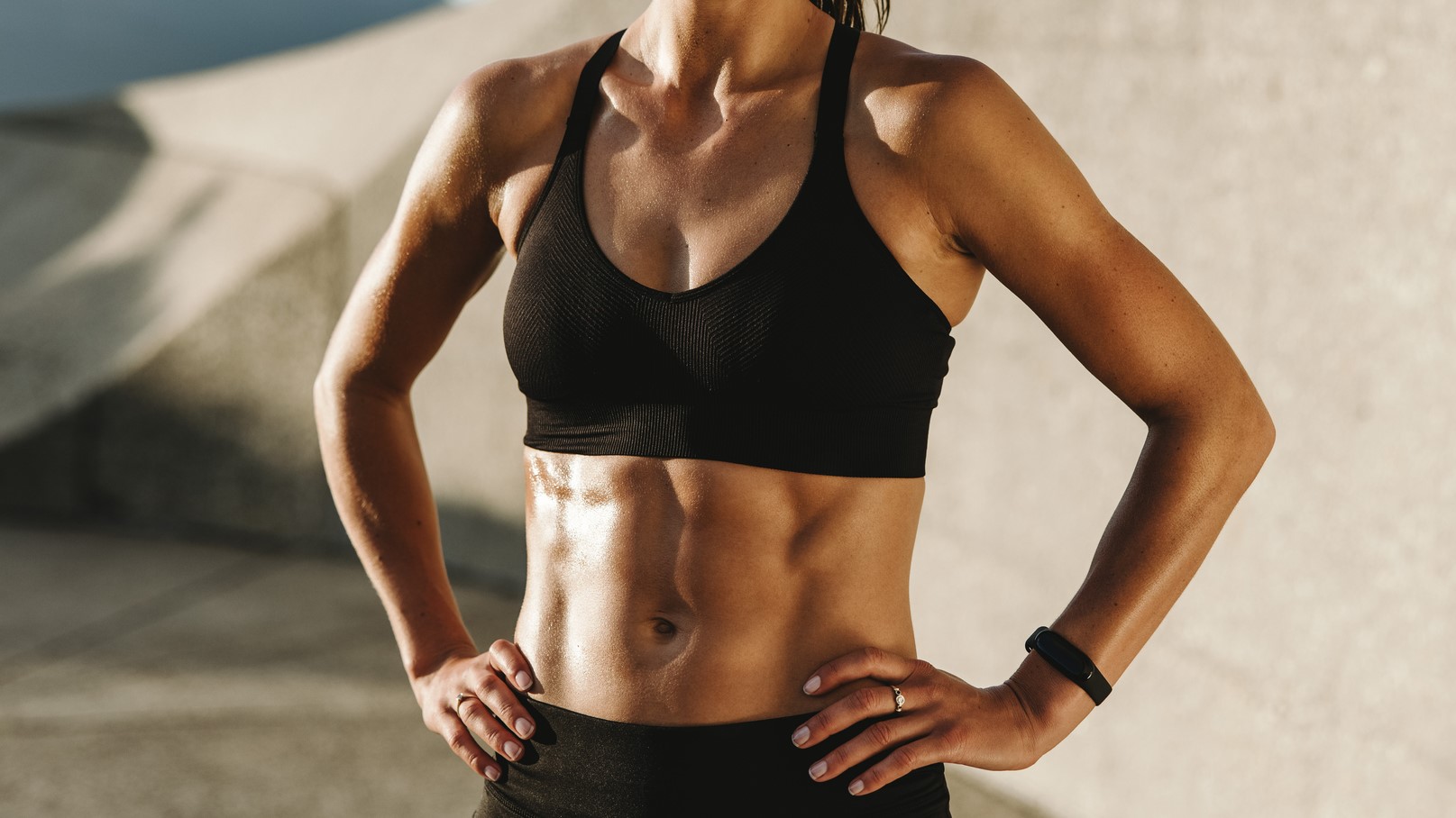 Woman outdoors in sunshine in a sports bra with her abs on show