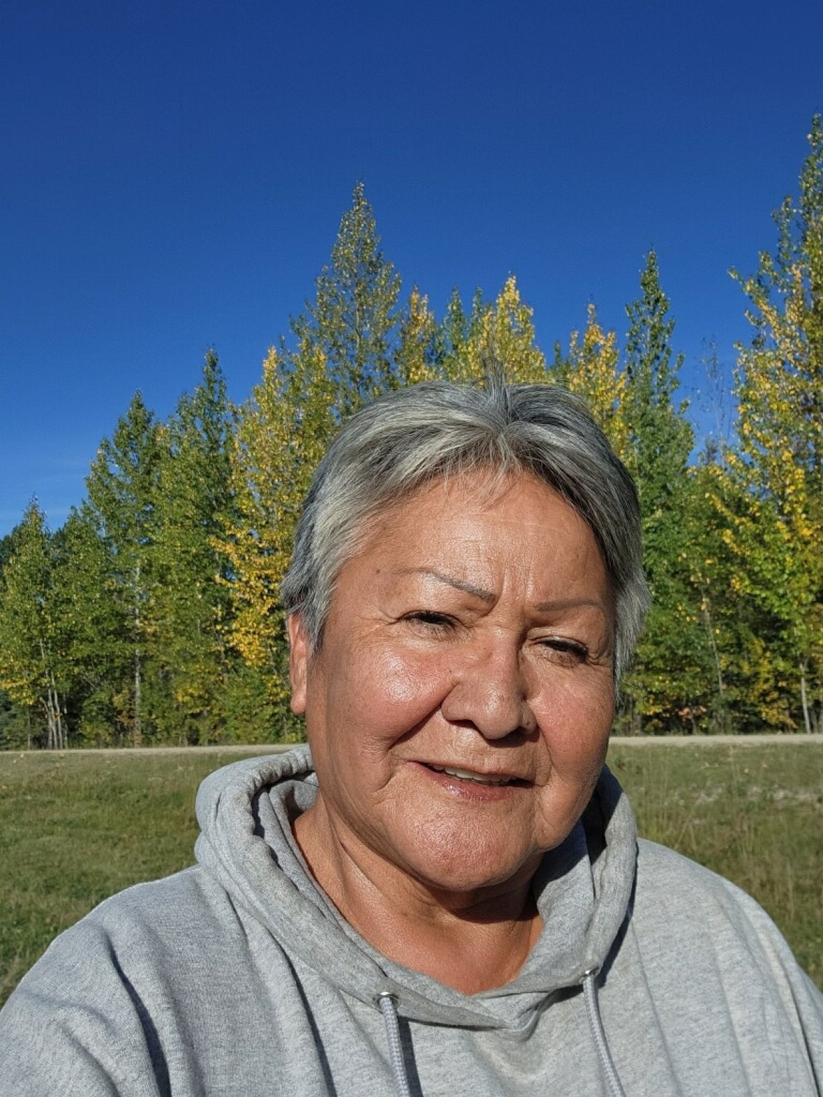 A photo of a woman wearing a grey hoodie.