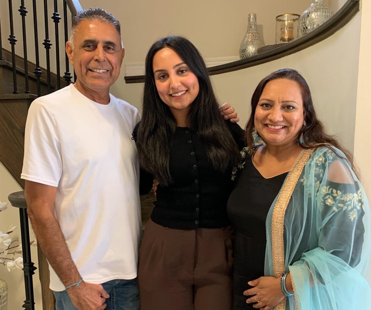 A young woman with her parents pose for a photo.