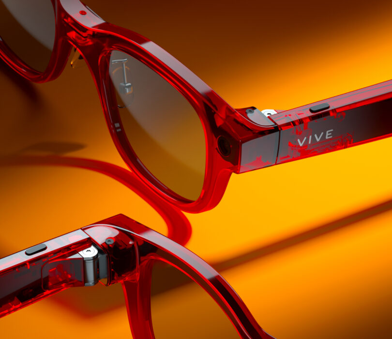 Close-up of two pairs of red, translucent smart glasses with "VIVE" branding, displayed against a gradient orange background.