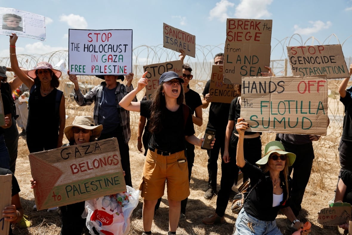 Demonstrators hold signs as they attend a protest near a border.