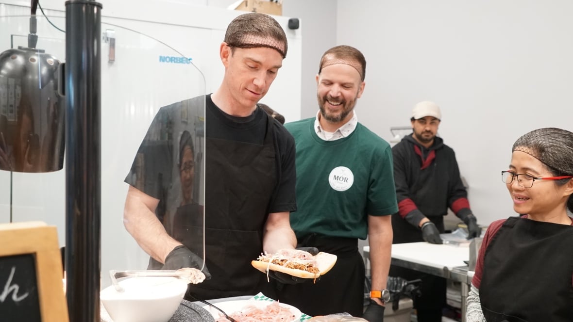 A group of people making a sandwich.