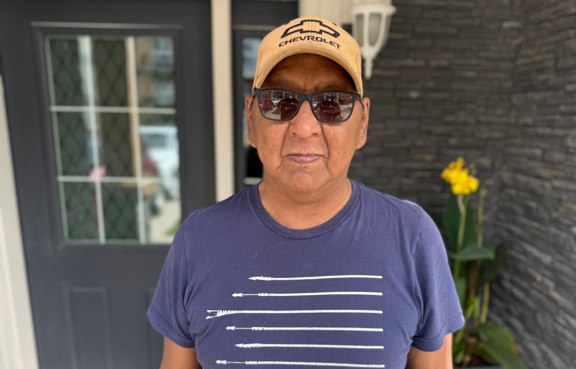 An Inuit man standing outside in front of his home.