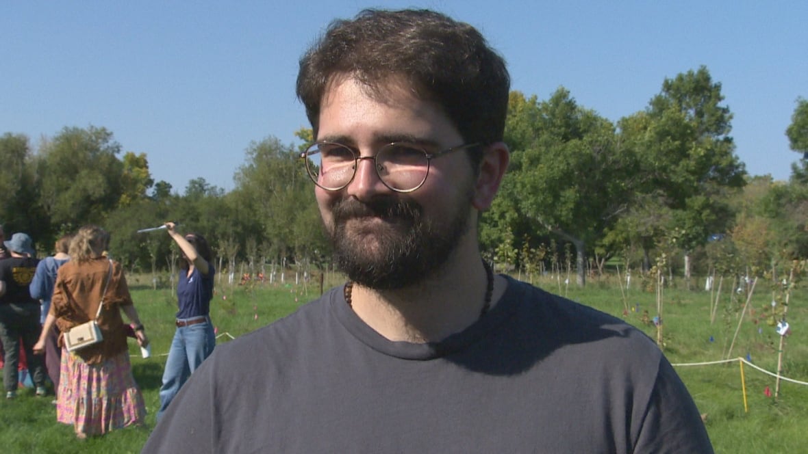 A young man with glasses is smiling. 