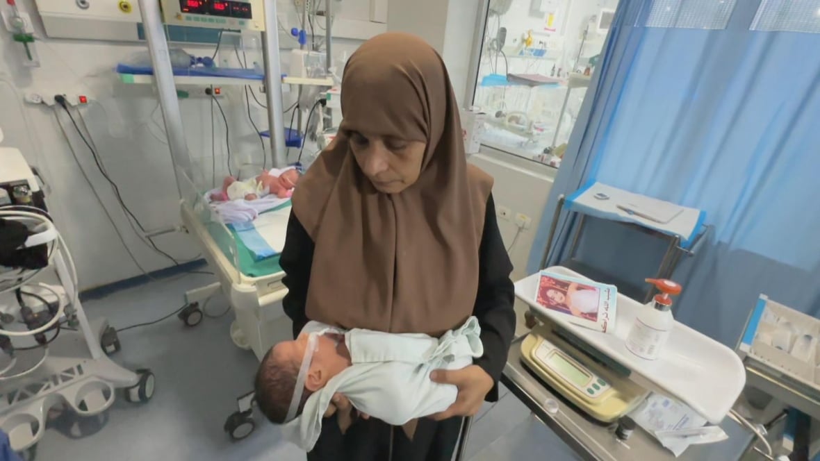 A woman holds an infant in her arms at a hospital.