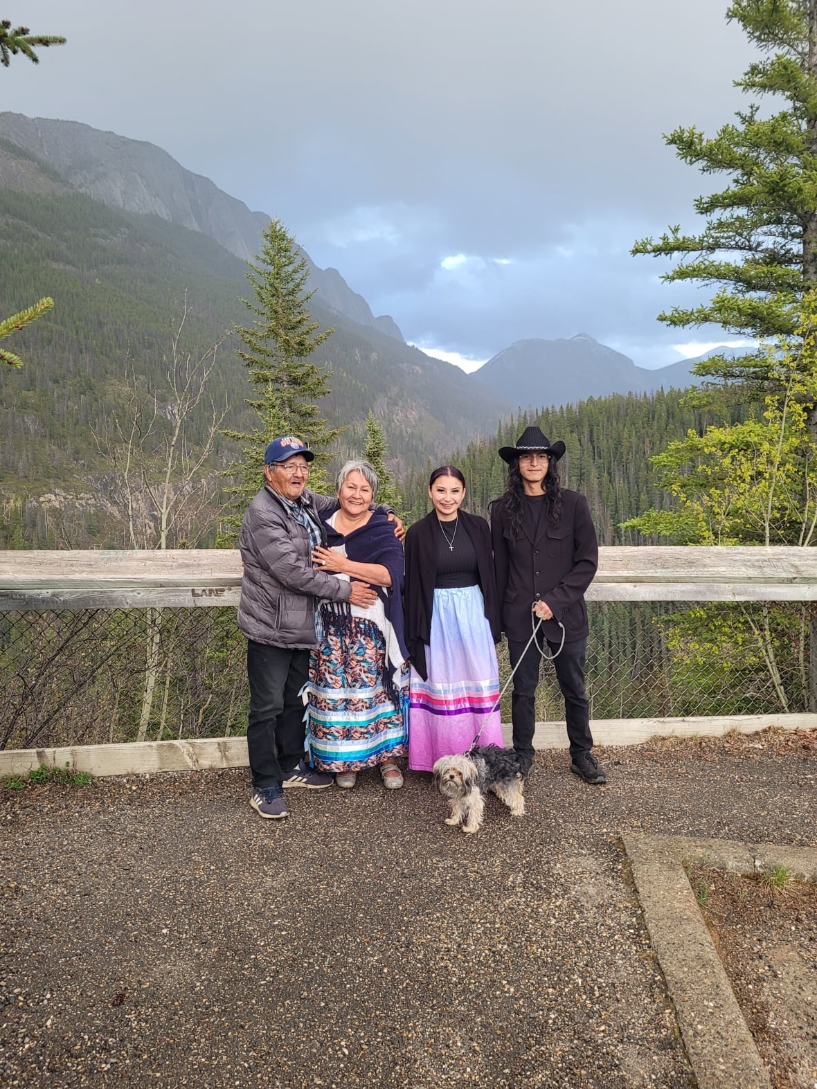 A photo of a group of people standing in front of a fence with a mountain in the backdrop.