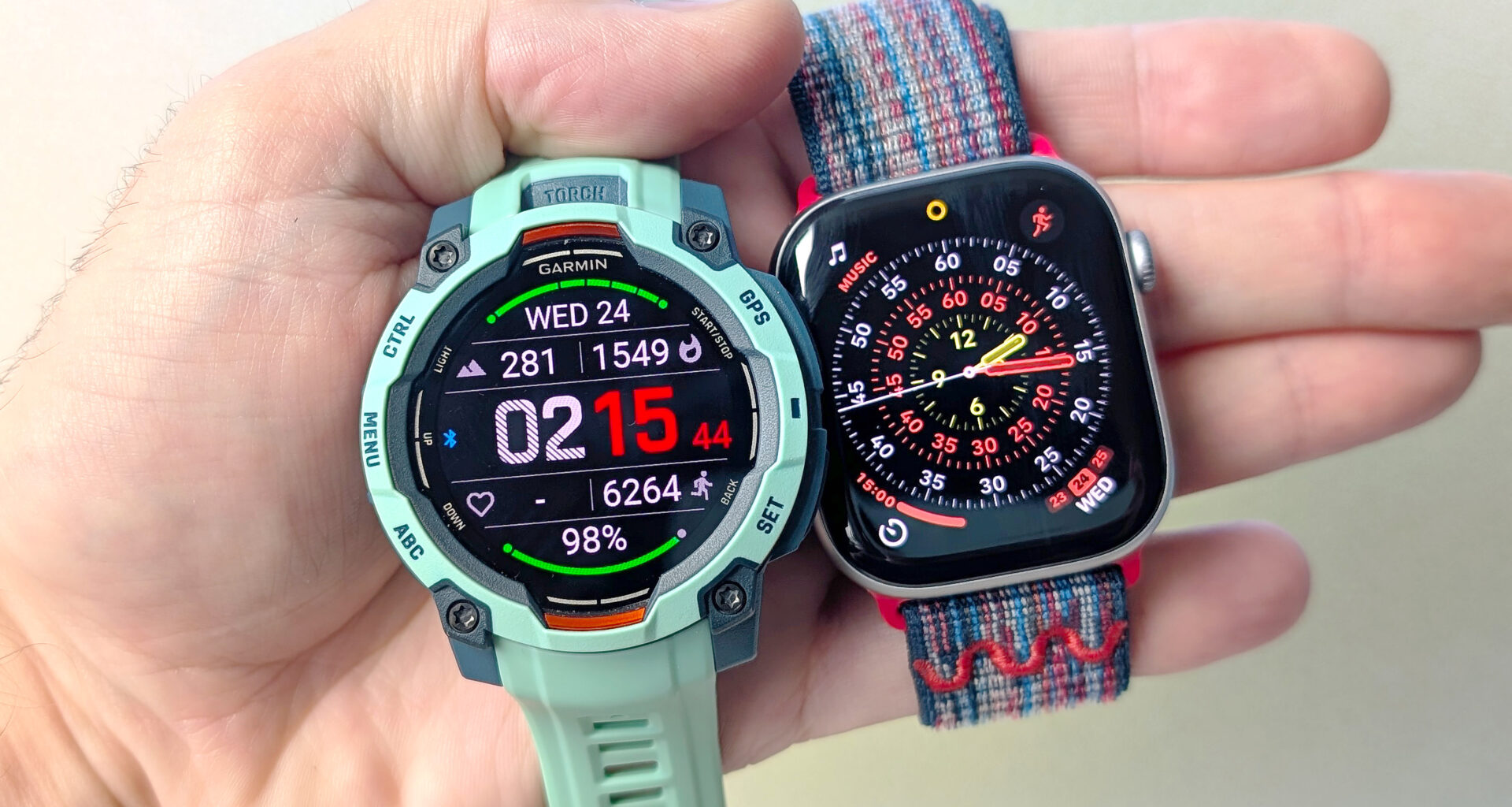 Close-up of the Garmin Instinct 3 next to the Apple Watch Series 11