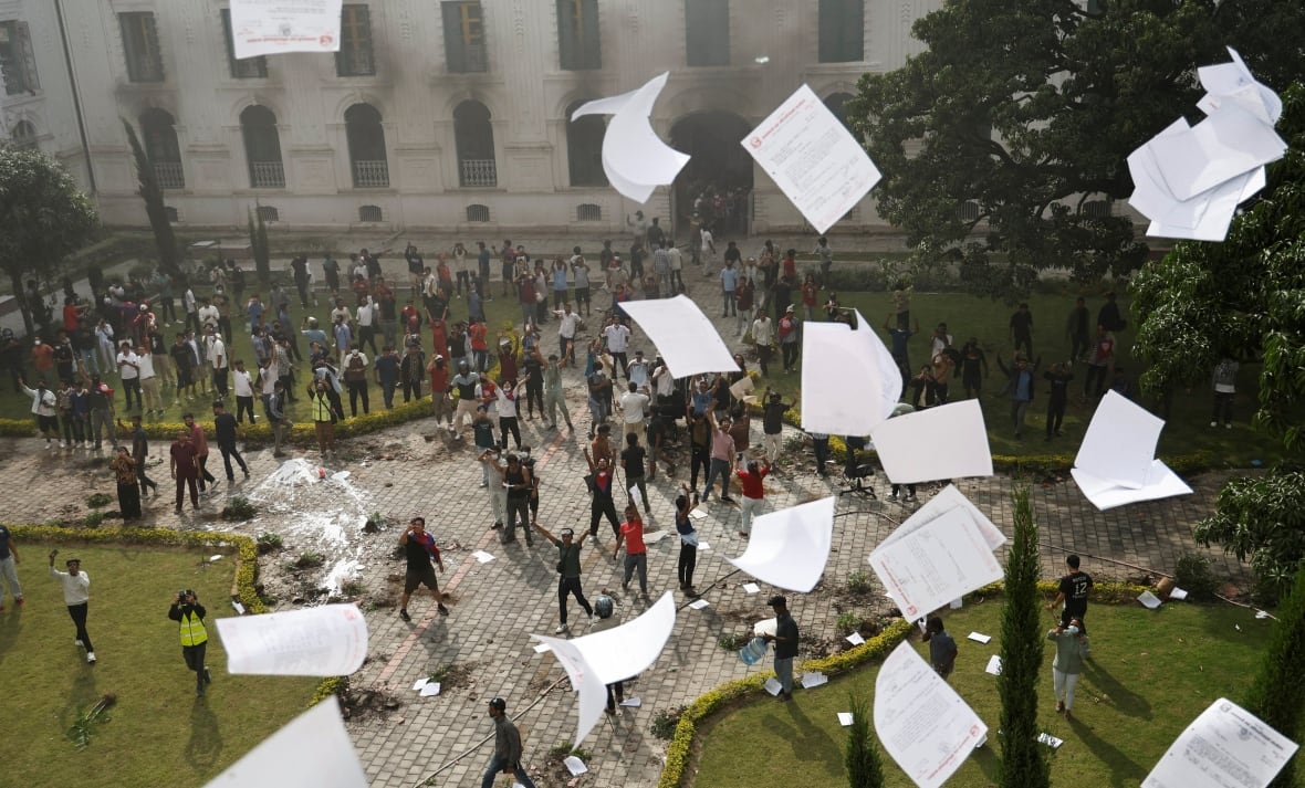 Paper rains down on a crowd of protesters, gathered in a large square.