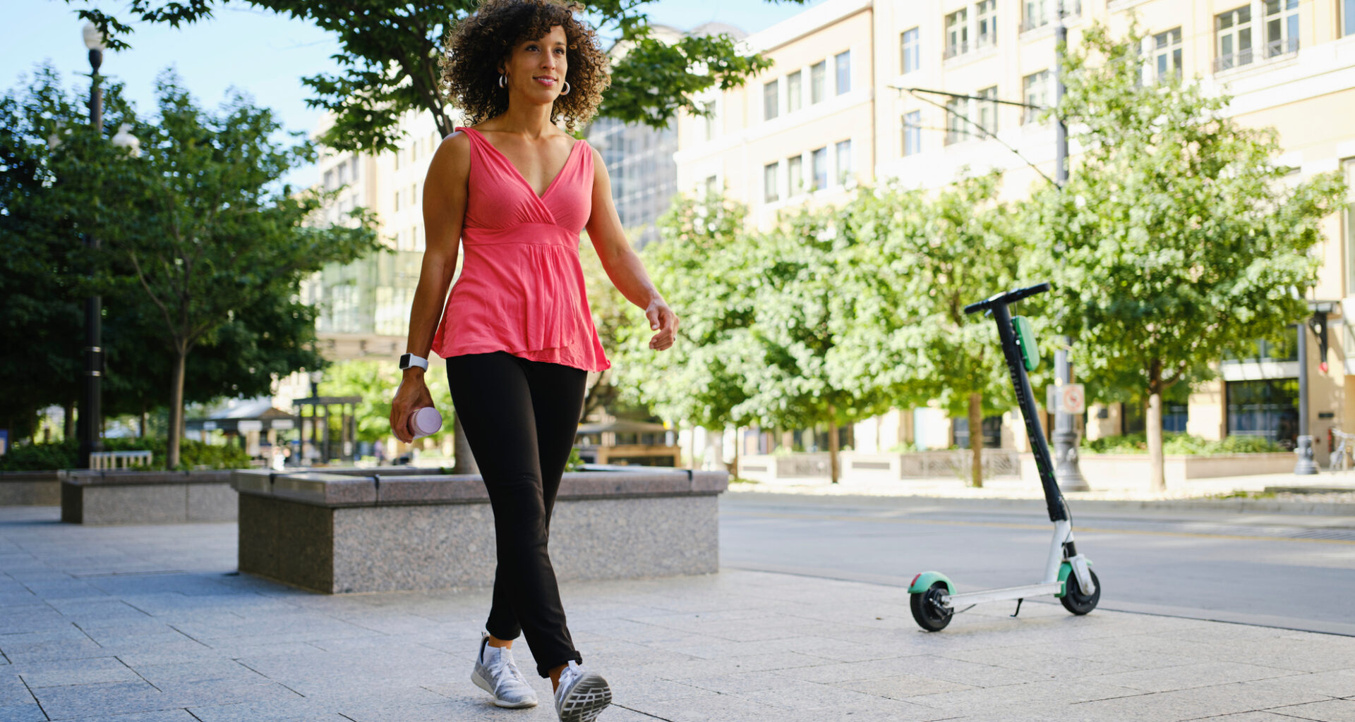 Woman walking in city on sunny day