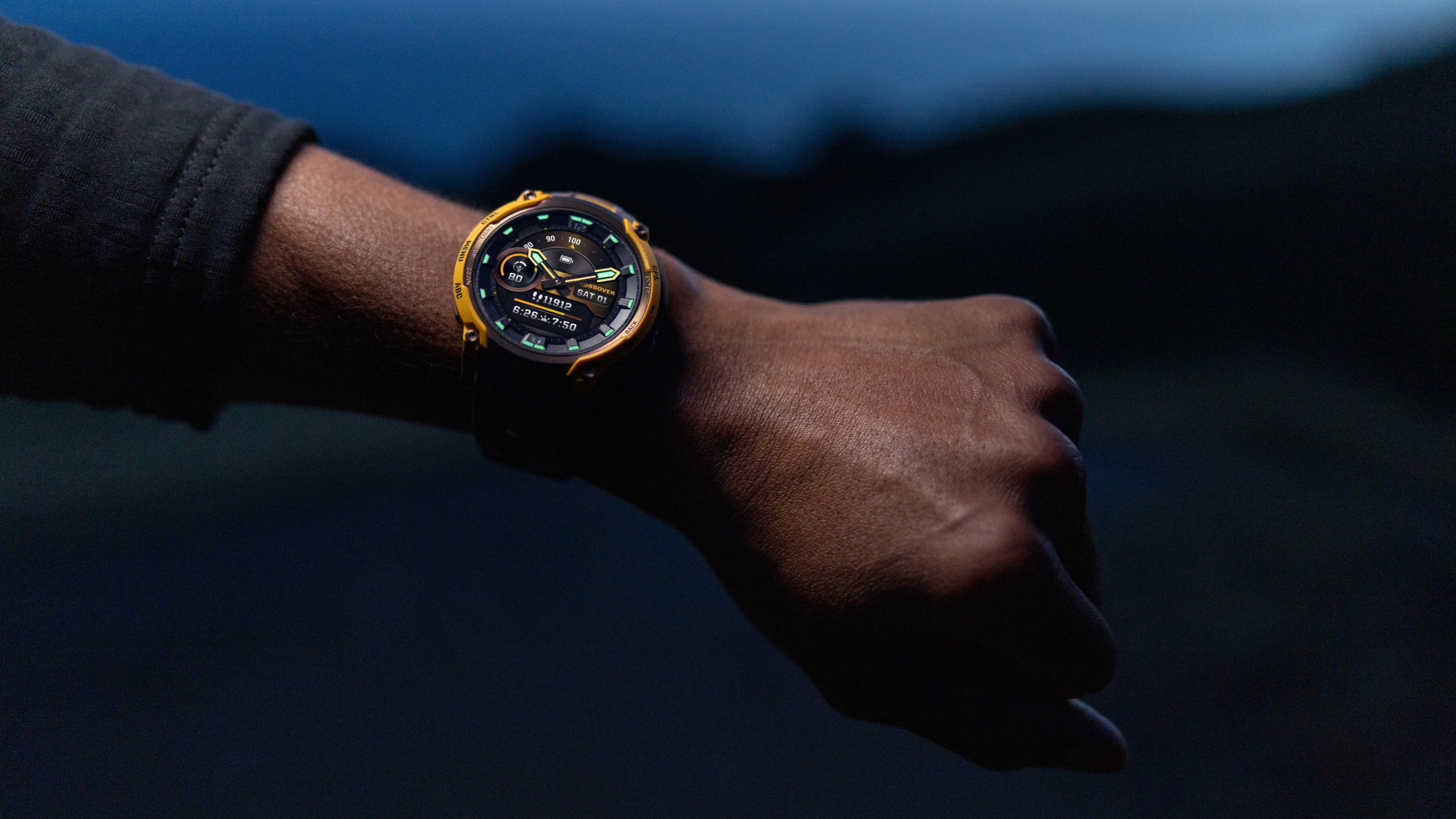 A photo of the Garmin Instinct Crossover AMOLED watch on a person's arm at night.