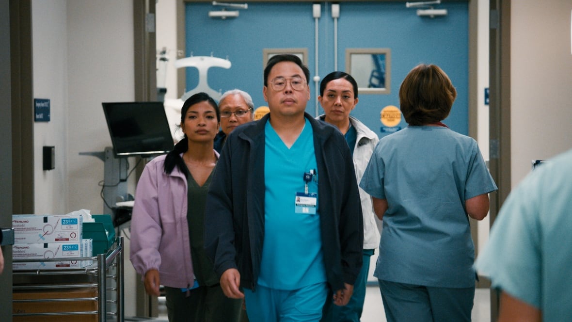 Four nurses in scrubs walking down hospital hallway. 