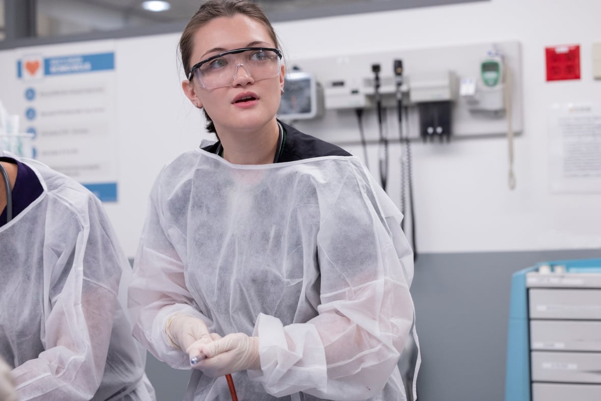 Doctor wearing protective glasses and surgical gown in emergency department trauma room.